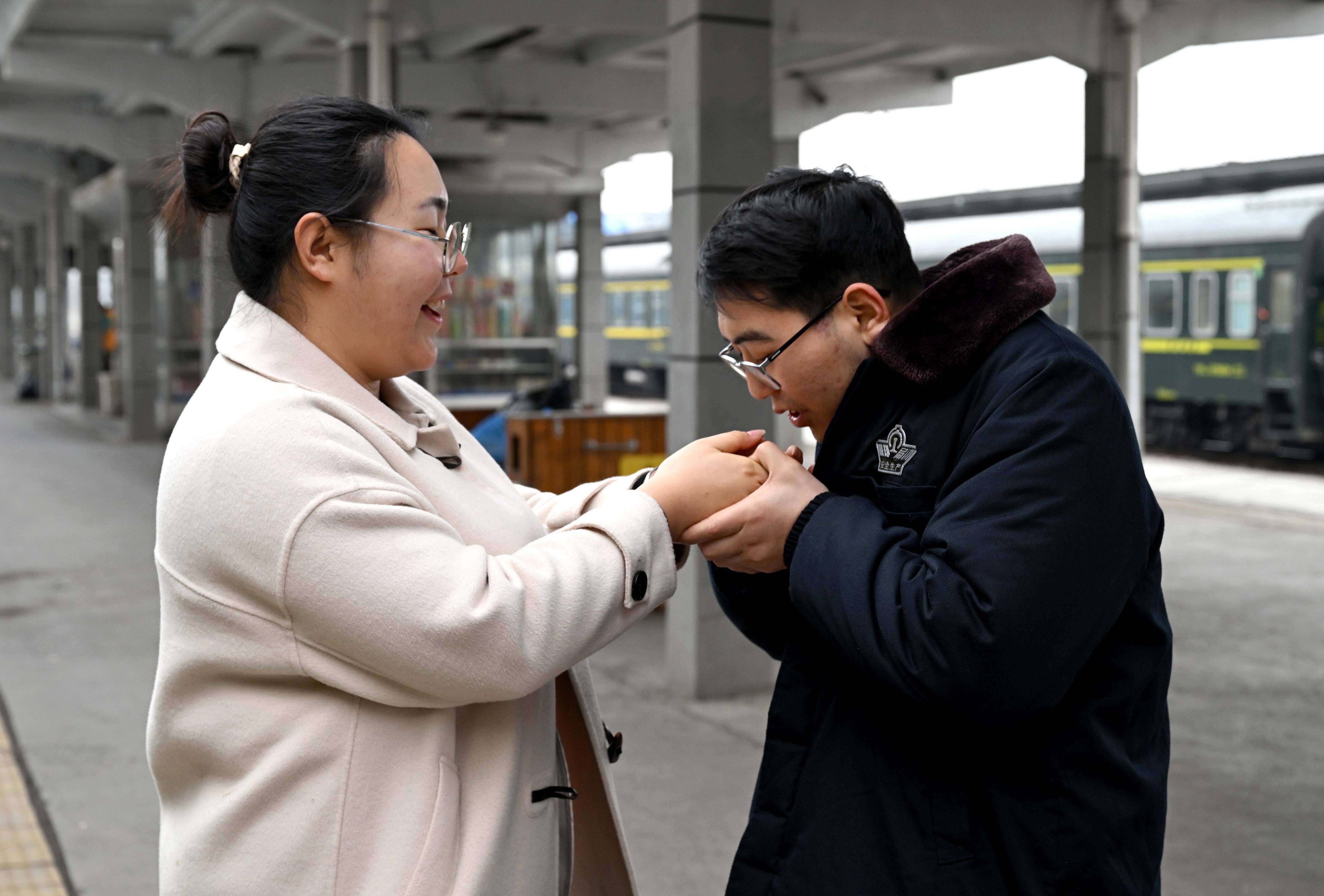 在新乡站站台上,杜永其给苏媛婷哈气暖手(2月1日摄)